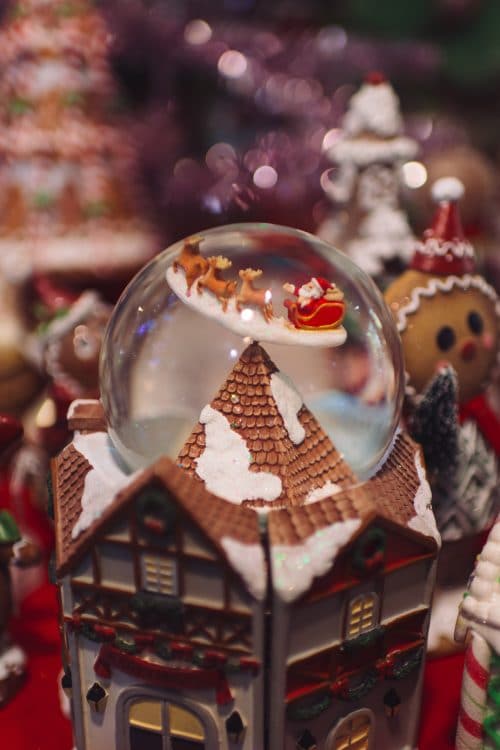 Boule à neige avec le père Noël et son traineau posé sur une maison miniature