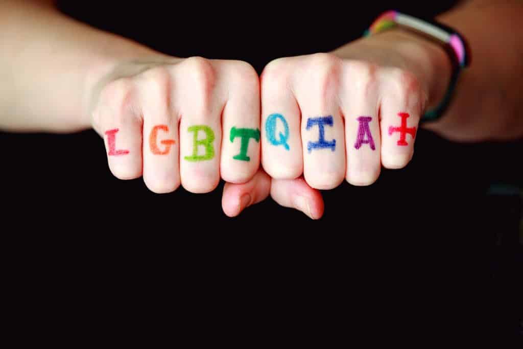 Mains ayants des faux tatouages LGBT sur les phalanges