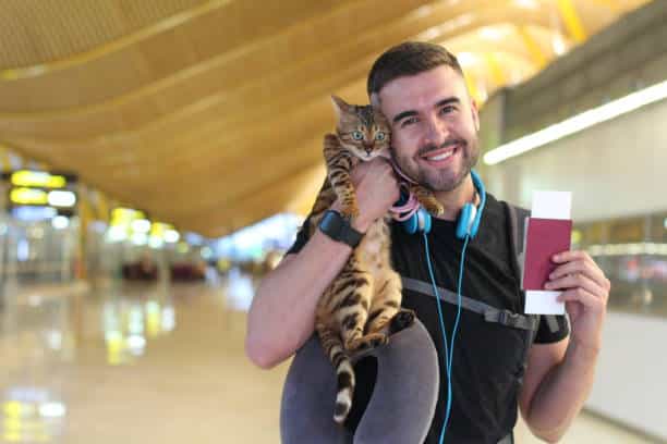 Homme souriant avec son chat dans le couloir d'un aéroport qui vont prendre l'avion