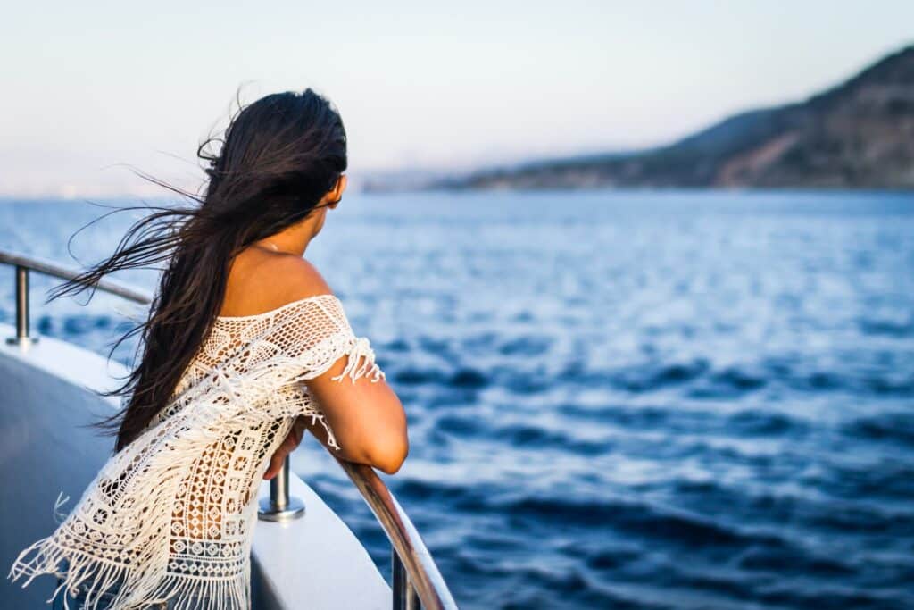 Femme à bord d'un bateau de croisière qui regarde la terre ferme avant d'aller en excursion