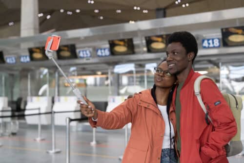Jeune couple se prenant en selfie à l'aéroport pendant un voyage à l'étranger