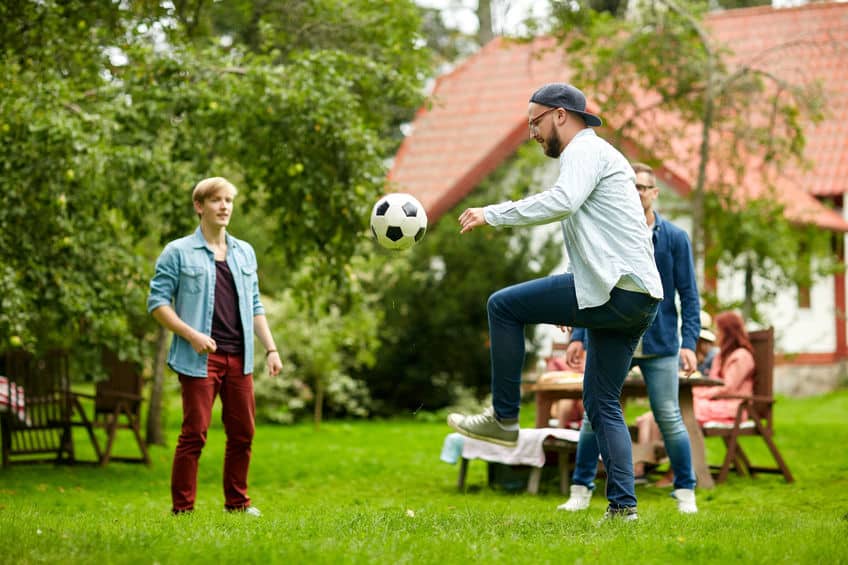 Amis jouants au football dans le jardin de la location chez l'habitant pendant leurs vacances en France