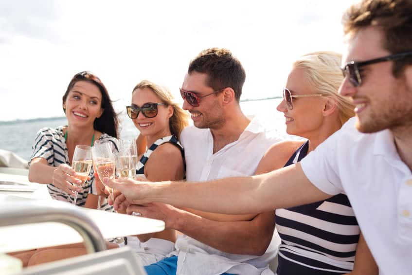 Groupe de jeunes adultes en vacances en France faisant du bateau et buvant du champagne